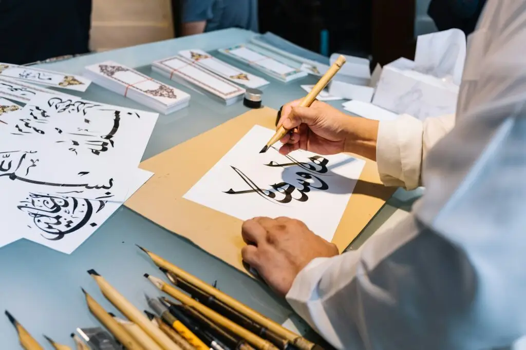 Man writing traditional Arabic character